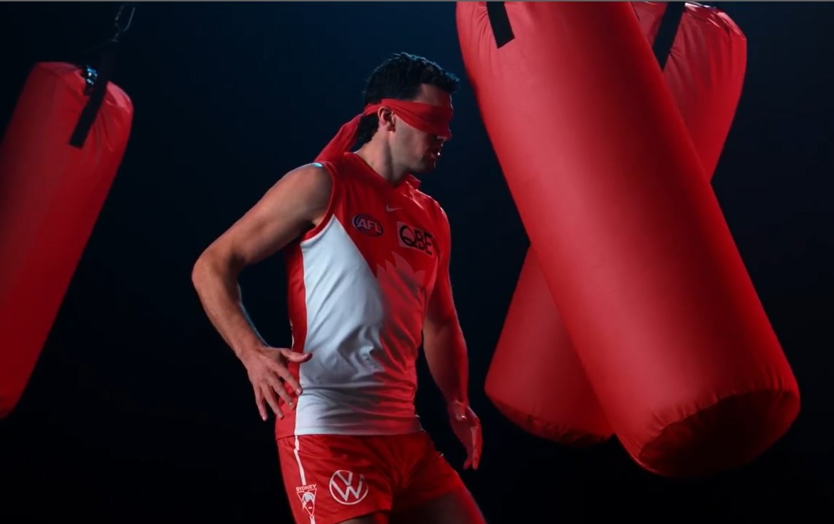 Sydney swans player running blindfolded through boxing bags