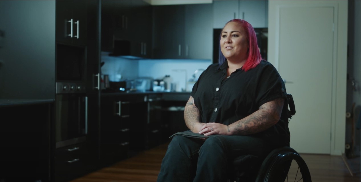 Image of Heidi sitting in her wheelchair in her kitchen.